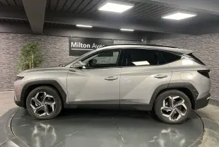 Profil côté gauche du Hyundai Tucson gris métallisé 2023 avec jantes alliage 19 pouces et toit noir contrasté.