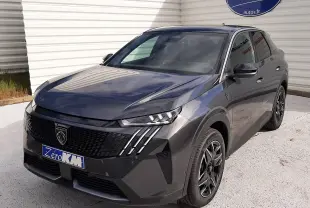 Peugeot 3008 gris titane en 3/4 avant droit, avec calandre noire et feux LED à griffes distinctifs.