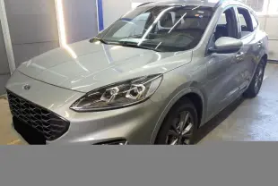 Vue 3/4 avant droite du Ford Kuga 2024 gris Solar avec calandre noire et phares Full LED visibles en intérieur.