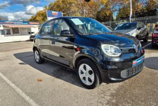 Renault Twingo Electric Zen noire vue en 3/4 avant droit sur parking avec ciel partiellement nuageux.