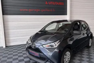 Toyota Aygo 1.0 VVT-i x-black gris foncé vue 3/4 avant droit dans un garage avec sol à damier.