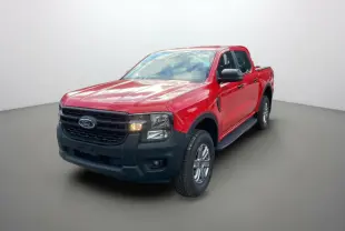 Ford Ranger 2025 rouge racing en 3/4 avant droit, avec calandre noire et phares allumés sur fond neutre.