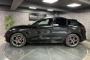 Profil côté gauche d'un Alfa Romeo Stelvio Veloce 2024 noir métallisé avec jantes 20 pouces et étriers rouges Brembo.