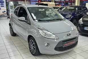 Vue 3/4 avant droite d'une Ford KA+ gris clair exposée en showroom avec jantes alliage et calandre noire.