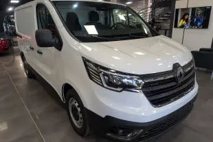 Renault Trafic Fourgon blanc glacier vu en 3/4 avant droit dans un showroom avec calandre noire distinctive.
