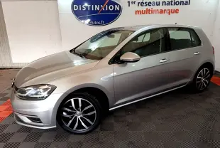 Volkswagen Golf gris clair vue de profil côté gauche, avec jantes alliage et phares allumés.