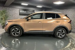 Profil latéral gauche d'un Kia Sportage marron métallisé 2022 avec jantes alliage 17 pouces et protections noires.