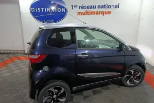 Profil droit d'une Aixam City Pack Premium 482d noire avec toit blanc et jantes alu dans un showroom.