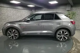 Vue de profil côté gauche d'un Volkswagen T-Roc gris métallisé avec jantes alliage 19 pouces et finitions R-Line.