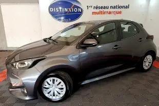 Toyota Yaris hybride gris clair vue de profil côté gauche, avec logo Hybrid et feux avant allumés.