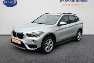 BMW X1 18i gris argent métal en 3/4 avant droit, avec jantes alliage et calandre noire distinctive.