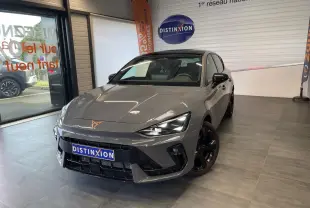 Vue 3/4 avant d'une CUPRA Leon gris Graphène avec jantes cuivrées et logo CUPRA sur le capot, en showroom.