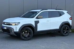 Dacia Duster ECO-G 120 Auto Extrême blanc glacier en vue 3/4 avant droit avec jantes noires et barres de toit.