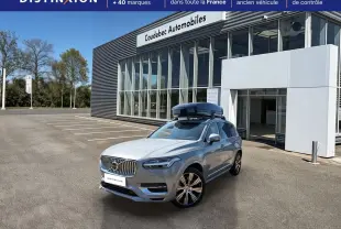 Vue 3/4 avant droite du Volvo XC90 gris avec coffre de toit noir sur parking devant concession.