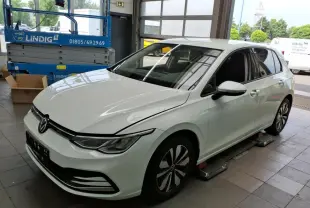 Volkswagen Golf 8 blanche vue 3/4 avant droit en intérieur avec jantes distinctives et phares LED.