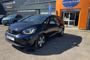 Honda Jazz 1.5 i-MMD bleu nuit nacré vue 3/4 avant droit, avec phares LED et jantes alu devant un garage Distinxion.