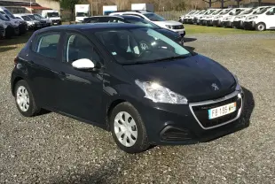 Peugeot 208 gris hurricane vue 3/4 avant droit sur parking, avec rétroviseurs blancs et jantes alliage.