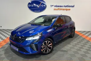 Renault Clio V E-Tech hybride bleu Iron Metal, vue 3/4 avant droit avec phares LED allumés en showroom.