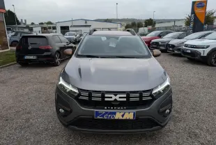 Vue frontale d'une Dacia Sandero Stepway gris schiste avec feux LED allumés et calandre noire distinctive.