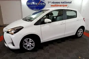 Toyota Yaris blanche 2020 vue de profil côté gauche dans un showroom avec éclairage intérieur.