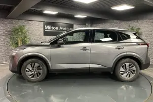 Profil côté gauche d'un Nissan Qashqai gris 2023 en showroom, soulignant ses lignes modernes et jantes alliage 17 pouces.