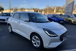 Vue 3/4 avant d'une Suzuki Swift blanche 2025 hybride essence, garée en extérieur sur un parking de concession.
