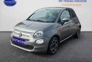 Fiat 500 gris vue 3/4 avant droit, avec jantes distinctives et phares ronds allumés.