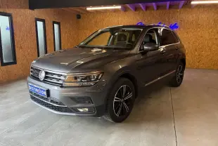 Volkswagen Tiguan gris 3/4 avant droit, avec jantes noires et détails chromés, en intérieur sur sol béton.