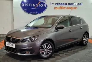 Peugeot 308 gris foncé vue 3/4 avant droit dans un showroom avec logo Distinxion en arrière-plan.