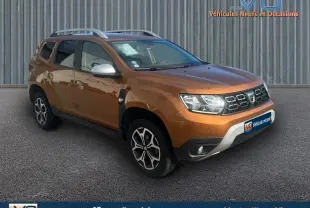 Dacia Duster TCe 125 4x2 Prestige orange en 3/4 avant droit avec barres de toit et jantes alliage 17 pouces.