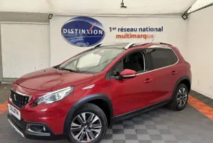 Peugeot 2008 rouge vue 3/4 avant droit, avec jantes alliage et barres de toit chromées en intérieur showroom.