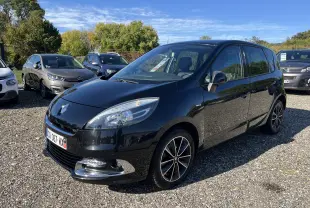 Renault Scenic III noir en 3/4 avant droit, avec jantes alliage et calandre chromée brillante sous un ciel dégagé.