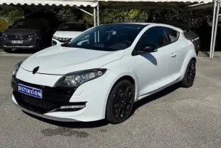 Renault Mégane III Coupé 2.0T RS blanc nacré en 3/4 avant droit avec jantes noires et phares Xenon visibles.