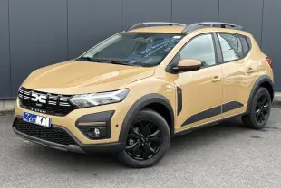 Vue 3/4 avant droite d'une Dacia Sandero Stepway beige Safari avec jantes noires et barres de toit gris Mégalithe.