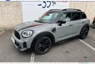 Mini Countryman Cooper gris vue 3/4 avant droit avec jantes noires et toit noir stationné sur parking.