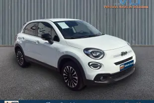 Fiat 500X blanc vue 3/4 avant droit, jantes stylées et phares ronds distinctifs sur fond urbain.