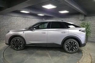 Peugeot 3008 gris en profil droit dans un showroom, avec jantes alliage noires et toit noir contrasté.