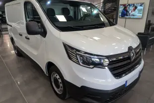 Renault Trafic Fourgon blanc minéral vu en 3/4 avant droit, avec calandre noire et phares modernes, en showroom intérieur.