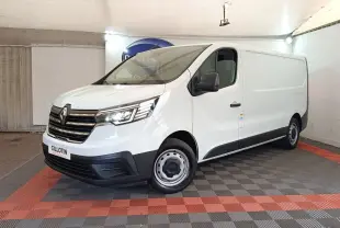 Renault Trafic Fourgon blanc vu en 3/4 avant droit, avec calandre chromée et phares LED allumés dans un showroom.