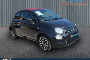 Vue 3/4 avant d'une FIAT 500C noire avec toit rouge et jantes alliage stylées, stationnée sur sol bitumé.