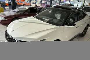 Vue 3/4 avant droite d'une DS4 E-Tense 2023 avec toit noir Perla Nera et carrosserie blanche nacrée en showroom.