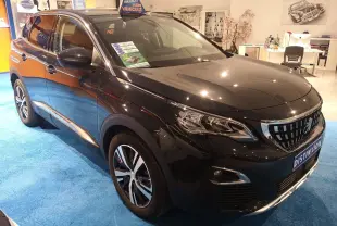 Peugeot 3008 gris hurricane en 3/4 avant droit dans un showroom avec jantes alliage et calandre chromée.