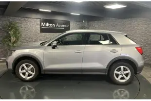 Profil côté gauche d'un Audi Q2 gris métallisé 2019 avec jantes 16 pouces et protections noires sur les passages de roues.