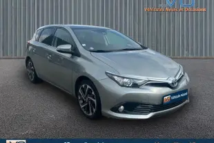 Vue 3/4 avant d'une Toyota Auris Business Hybride gris clair avec jantes alliage 17 pouces sur sol gris.