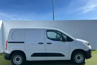 Vue 3/4 avant d'un utilitaire Citroën Berlingo blanc Icy avec pare-chocs noir devant un bâtiment Distinxion.