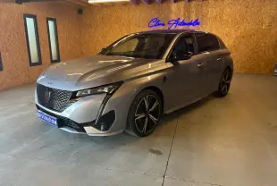 Peugeot 308 gris vue 3/4 avant droit en intérieur, avec calandre distinctive et jantes noires bicolores.