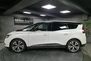 Profil droit d'un Renault Scénic blanc nacré avec toit noir et jantes alliage 20 pouces dans un showroom.