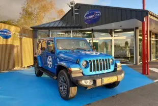 Jeep Wrangler 2.0 T 380ch 4xe Sahara Command-Trac bleu Hydro Blue vue 3/4 avant sur parking devant concession Distinxion