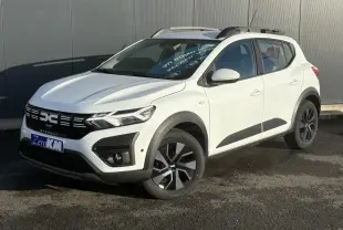 Vue 3/4 avant droite d'une Dacia Sandero Stepway 2024 blanc glacier avec barres de toit et jantes noires.