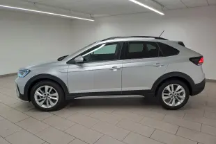 Vue de profil côté gauche d'un Volkswagen Taigo 2025 en peinture métallisée Reflet d'argent avec jantes alliage et toit noir.